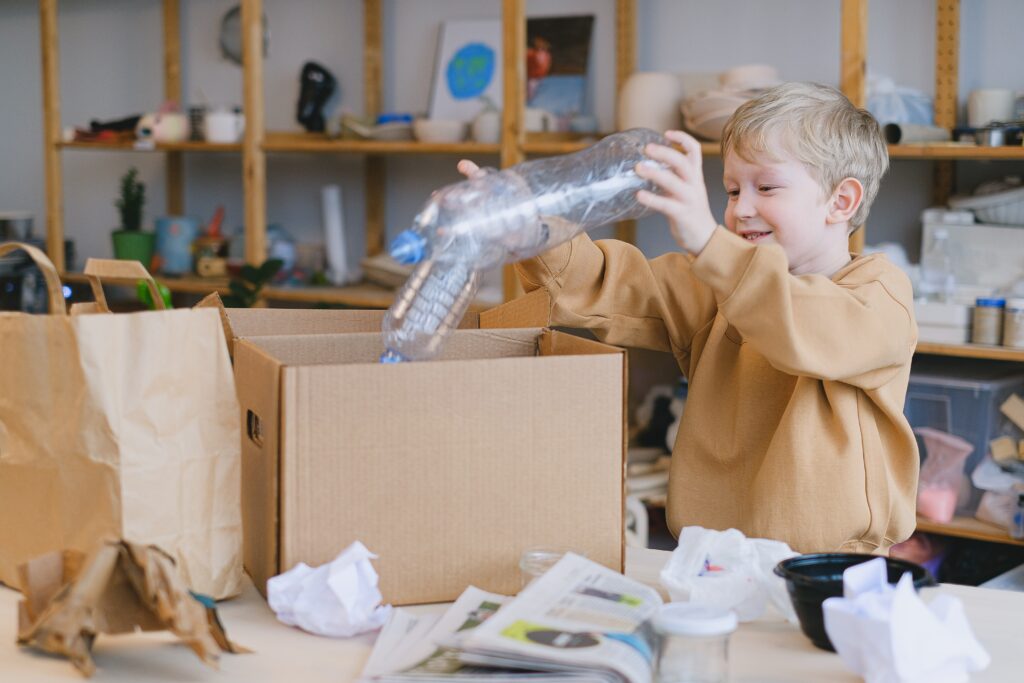 A young boy placing plastic bottles in a box