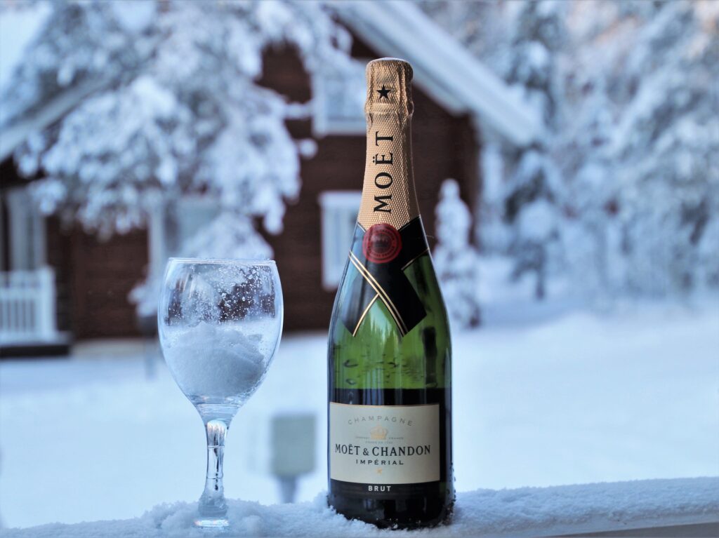 A glass and bottle of champagne against a cold winter background