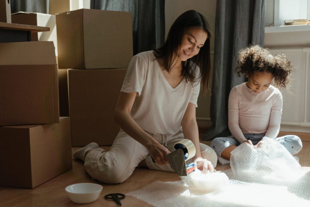 A woman and child wrapping dishware with bubble wrap