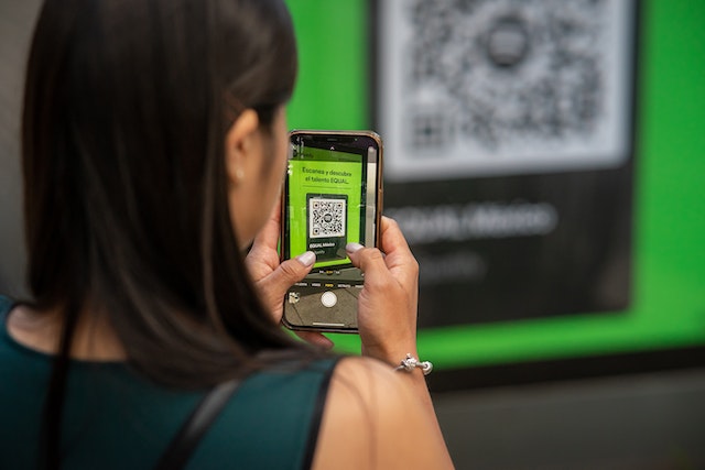Woman scanning QR code from a wall display
