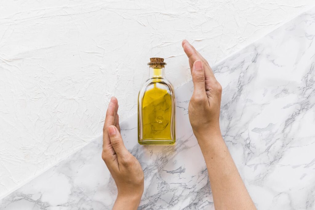 Two hands presenting a bottle of olive oil
