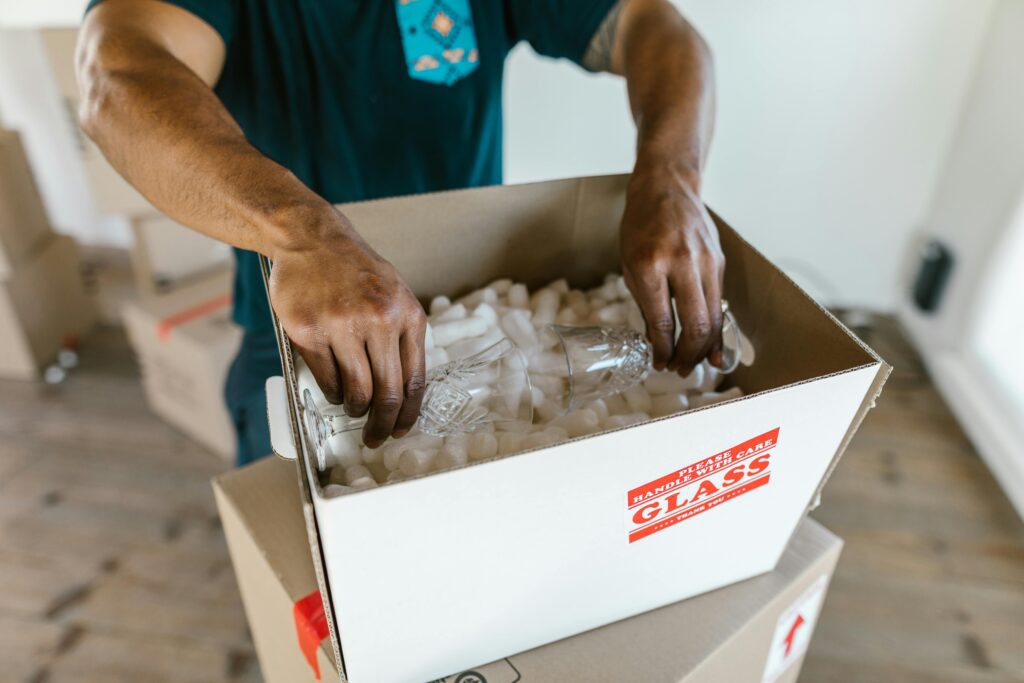 A person packing glassware inside a box